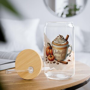 May include: A clear glass can-shaped cup with a bamboo lid and straw. The cup features a fall-themed design with a coffee cup, pumpkins, and the text "Delight in the Lord". The design includes brown, orange, and beige colors.