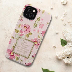 May include: A pink floral phone case with a light pink background. The case features pink flowers and green leaves. The case has a rectangular text box with the words "Seek the Lord and his strength; seek his presence continually!"