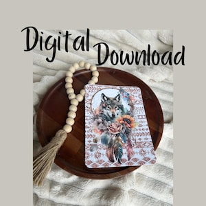 May include: A digital download featuring a watercolor illustration of a wolf's face in a dreamcatcher with feathers and flowers. The background is a pink and white patterned design.