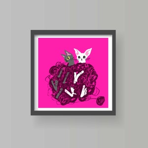 May include: A framed print featuring two stylized cats amidst a ball of pink yarn on a vibrant pink background. One cat is gray with yellow eyes, the other is white. The artwork is framed in a dark gray frame.