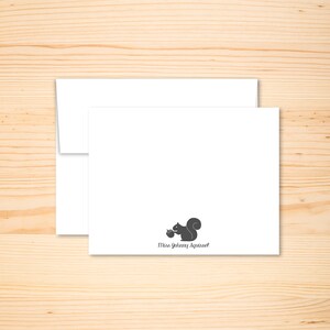 May include: A white card with a black silhouette of a squirrel holding an acorn. The text "Miss Johnny Squirrel" is printed below the squirrel.