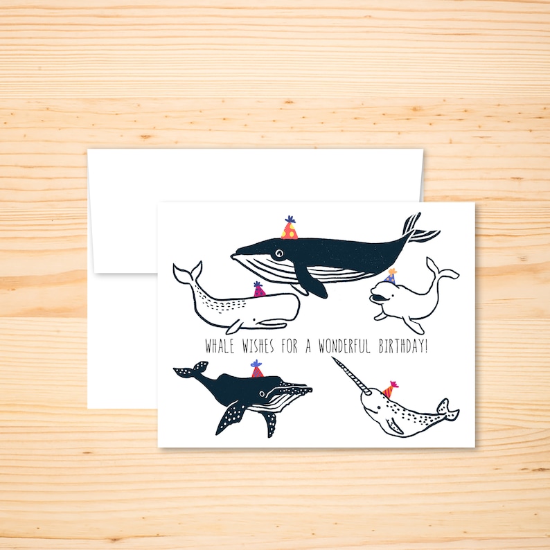 May include: A birthday card featuring a black and white illustration of four whales wearing party hats. The text on the card reads "Whale wishes for a wonderful birthday!"