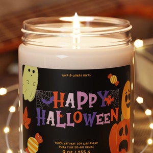 May include: A glass candle jar with a black label that says "Happy Halloween" and features a ghost, bats, pumpkins, and candy. The candle is lit and the jar is sitting on a wooden coaster.