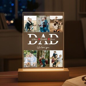 Op de afbeelding: Een rechthoekige acryl fotodisplay met een verlichte houten voet. Het display bevat zes individuele familiefoto's in twee rijen, met de tekst DAD, de namen William, Elizabeth en James, en de zin We love you.
