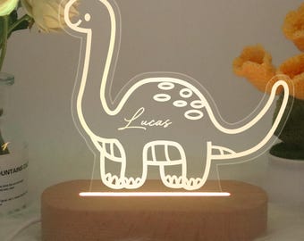 May include: A white wooden night light shaped like a dinosaur with the name "Lucas" written on it. The light is on and illuminating the dinosaur.