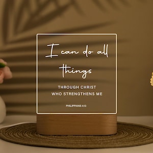 May include: A lighted sign with the text "I can do all things through Christ who strengthens me" in white script. The sign is rectangular with a wooden base and a clear acrylic front. The text is from Philippians 4:13.