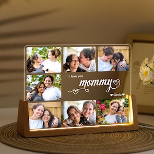 May include: A wooden-based photo display with a clear acrylic panel featuring multiple family photos. The panel has the words "I love you mommy" and a heart design. The base has a warm, glowing light.