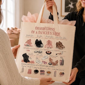 Puede incluir: Un bolso tote beige con una ilustración detallada de varios zapatos y accesorios de ballet. El texto "OBSERVATIONS OF A DANCER'S SHOE" está impreso en la parte superior. El bolso es sostenido por dos personas.
