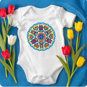 May include: White baby onesie with a colorful floral design. The design features a circular pattern with red, blue, yellow, and green elements. The onesie is surrounded by red, white, and yellow tulips on a blue background.
