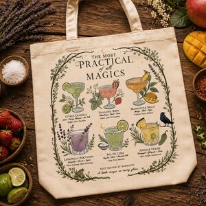 May include: Cream-colored tote bag with a botanical illustration of cocktail recipes. The bag features the text "THE MOST PRACTICAL of all MAGICS" and includes illustrations of various cocktails with their ingredients. The bag is surrounded by ingredients like strawberries, limes, and mango.