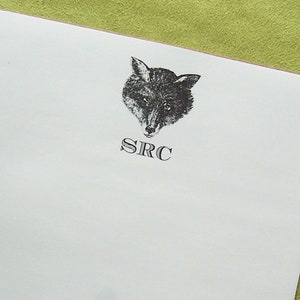 May include: White notepad with a black and white illustration of a fox's head and the text "SRC" printed on it.