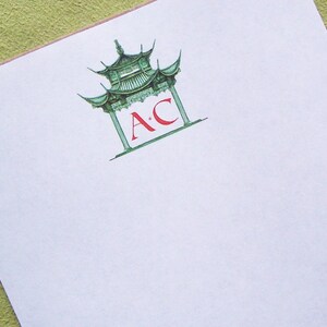 May include: A white notepad with a green pagoda illustration and the letters "A*C" in red.