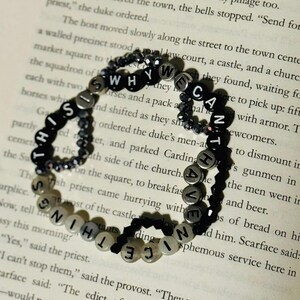 May include: A circular beaded bracelet featuring black and white letter beads that spell out the phrase THIS IS WHY WE CAN'T HAVE NICE THINGS. The bracelet is constructed with alternating black and white letter beads and small dark faceted beads.
