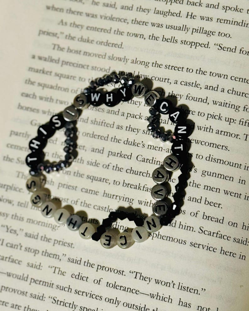 May include: A circular beaded bracelet featuring black and white letter beads that spell out the phrase THIS IS WHY WE CAN'T HAVE NICE THINGS. The bracelet is constructed with alternating black and white letter beads and small dark faceted beads.