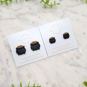 Puede incluir: Un par de pendientes de olla de oro negro con monedas de oro. Los pendientes son joyas de arcilla polimérica hechas a mano. El texto en la tarjeta dice "Happy Little Clay Co. Joyas de arcilla polimérica hechas a mano #HappyLittleClayCo www.etsy.com/shop/HappyLittleClayCo"