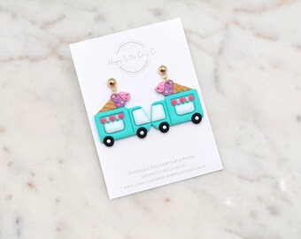 Puede incluir: Pendientes de arcilla polimérica hechos a mano con diseños de camiones de helados turquesa con conos de helado rosas y morados. Los pendientes tienen tachuelas doradas y ruedas negras. La tarjeta dice "Happy Little Clay Co."