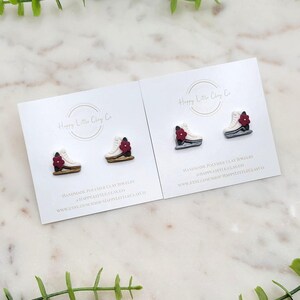 May include: Two pairs of handmade polymer clay earrings. Each earring is shaped like a white and brown sneaker with a red flower accent. The earrings are displayed on white cards with the text "Happy Little Clay Co."