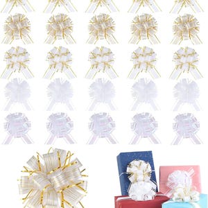 Puede incluir: Un surtido de lazos decorativos para regalo en blanco y dorado, dispuestos en filas. Algunos lazos se muestran en cajas de regalo envueltas en azul, rojo y rosa. Los lazos tienen un diseño similar a una cinta.