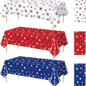 May include: Three rectangular tablecloths with a star pattern in red, white, and blue. The tablecloths are displayed on wooden tables. Each tablecloth has a different colour background: white, red, and blue. The star patterns are in contrasting colours.