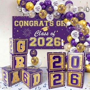 Puede incluir: Un conjunto de decoración para fiesta de graduación con detalles morados y dorados. Incluye bloques de letras que deletrean "GRAD" y los números "2026", una pancarta que dice "CONGRATS GR", y globos.