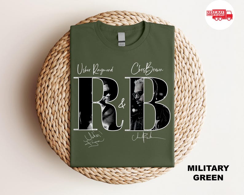 May include: Military green t-shirt featuring the text "R&B" with images of Usher Raymond and Chris Brown. The shirt includes the artists' signatures. The shirt is displayed on a woven surface.