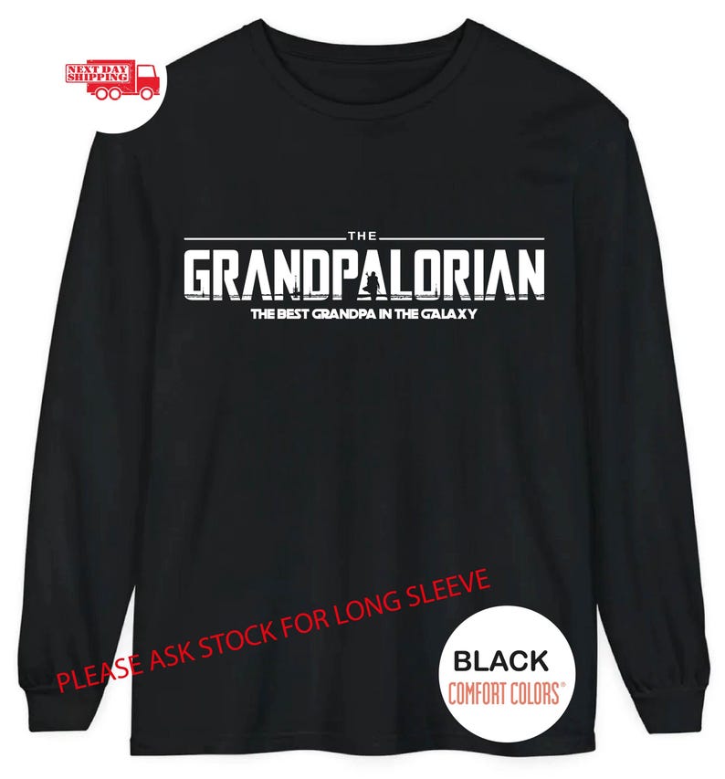 May include: Black long-sleeve t-shirt with white text that reads "THE GRANDPALORIAN THE BEST GRANDPA IN THE GALAXY". The text is in a bold, blocky font. The shirt also has the text "PLEASE ASK STOCK FOR LONG SLEEVE" and "BLACK COMFORT COLORS" in white.