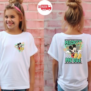 Puede incluir: Camiseta blanca con dise&ntilde;o de Mickey Mouse. La parte delantera tiene un peque&ntilde;o gr&aacute;fico de Mickey, mientras que la parte trasera muestra un dise&ntilde;o m&aacute;s grande con "Mickey Mouse" en letras verdes y negras. La camiseta tiene mangas cortas.