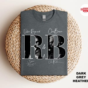 May include: Dark grey heather t-shirt featuring the text "Usher Raymond & Chris Brown R&B" in white. The shirt has black and white images of the artists. The words "Dark Grey Heather" are printed on the bottom right.