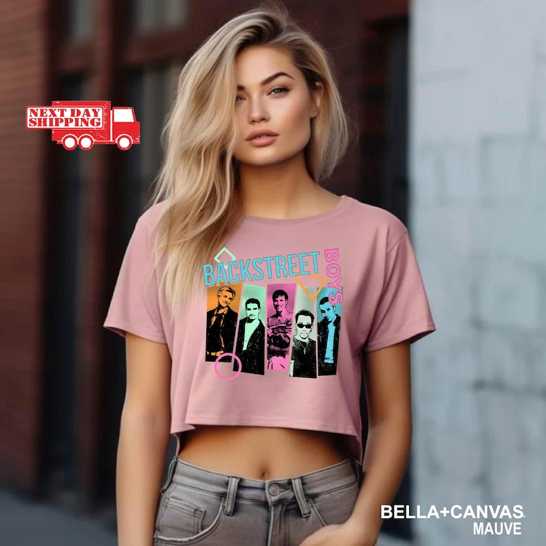 Puede incluir: Top corto color malva con la inscripci&oacute;n "BACKSTREET BOYS" en turquesa y blanco, y un gr&aacute;fico de los miembros de la banda. La camiseta es de material Bella+Canvas.
