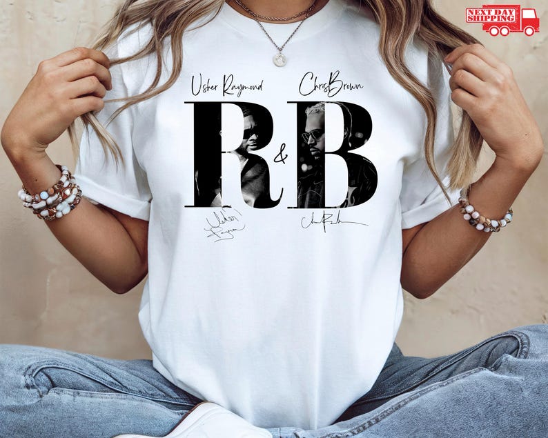 May include: White t-shirt featuring the text "Usher Raymond & Chris Brown R&B" in black, with black and white images of the artists within the letters. The shirt also includes the artists' signatures.