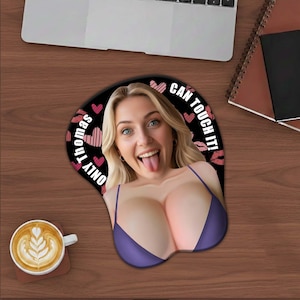 May include: A novelty mousepad featuring a woman with blonde hair and blue eyes, sticking out her tongue. The mousepad has a purple bra design and the text "ONLY Thomas CAN TOUCH IT!" is printed around the edge. The background is black with pink hearts and red lips.