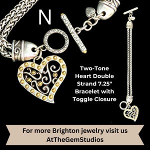 May include: A two-tone heart bracelet with a toggle closure. The bracelet has a double strand design and is 7.25 inches long. The heart charm is silver with gold accents. The text "Two-Tone Heart Double Strand 7.25" Bracelet with Toggle Closure" is visible.