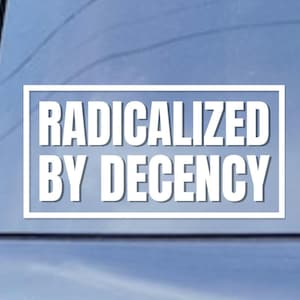 May include: White rectangular sticker with the words "RADICALIZED BY DECENCY" in bold, sans-serif font. The text is centered within a white border, set against a light blue background.