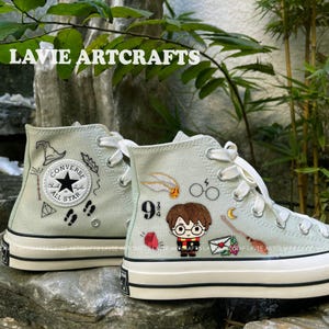 May include: A pair of light green high-top Converse sneakers with embroidered Harry Potter themed designs. The designs include Harry Potter, a golden snitch, a lightning bolt, and the number 9 3/4. The text "LAVIE ARTCRAFTS" is visible on the image.