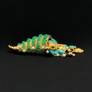 May include: A gold and green statement necklace with a turquoise and pearl drop. The necklace features a cone-shaped pendant with green beads and gold accents.