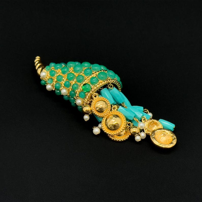 May include: A gold and green pendant with a teardrop-shaped design. The pendant is adorned with turquoise and pearl beads, and features a cascading design.