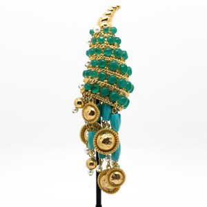 May include: A gold and green statement earring with a cascading design of turquoise and pearl beads. The earring features a gold horn-shaped base with green beads and a dangling section of turquoise and pearl beads.
