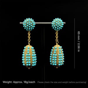 May include: A pair of gold-colored earrings with turquoise-colored beads. The earrings are 2.56 inches long and feature a chain design. Each earring weighs approximately 18 grams.