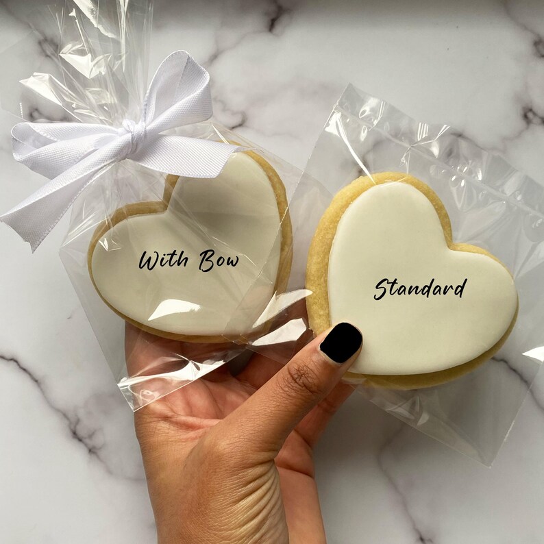 May include: Two heart-shaped cookies, one with a white bow and the text "With Bow" and the other with the text "Standard".