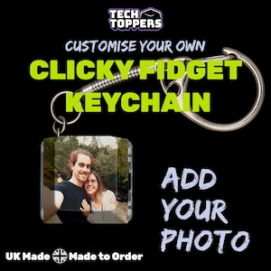 Peut inclure: Un porte-clés fidget personnalisable avec une photo. Le porte-clés a un anneau en métal argenté et un support photo carré transparent. Le texte de l'image indique "Personnalisez votre propre porte-clés Clicky Fidget" et "Ajoutez votre photo."