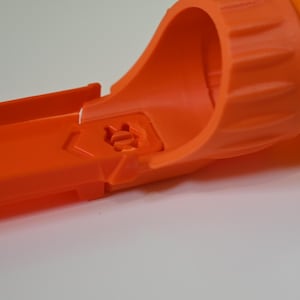 Peut inclure: Gros plan sur un morceau de piste de jouet en plastique orange. La piste a une section incurvée et une section droite, avec une pièce de connexion. La piste est conçue pour les voitures jouets et est en plastique durable.