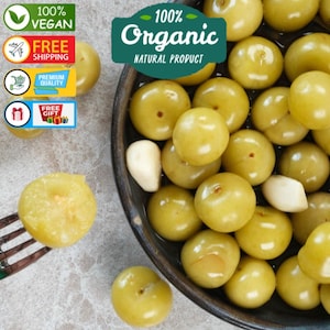 Peut inclure: Gros plan sur un bol rempli de groseilles à maquereau organiques jaune-vert et de quelques gousses d'ail. L'image comprend le texte "100% Organic Natural Product" et "100% Vegan".