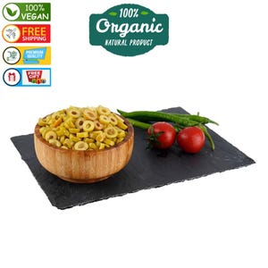 May include: A wooden bowl filled with green olives sliced into rings. The bowl is on a black slate surface with green peppers and red tomatoes.
