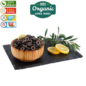 May include: A wooden bowl filled with black olives, a lemon wedge, and a sprig of olive leaves on a black slate surface. The text "100% Organic Natural Product" is visible in the top right corner of the image.