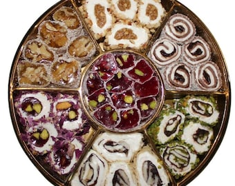 Puede incluir: Una bandeja redonda dorada llena de surtidos de delicias turcas. Los dulces están dispuestos en secciones e incluyen variedades con nueces, pistachos y rellenos de frutas. Los dulces son blancos, rojos, marrones y verdes.