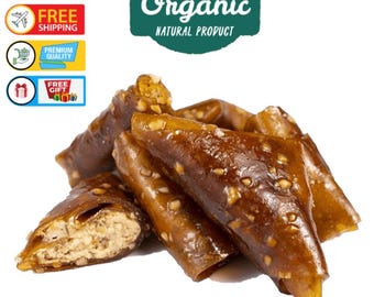Puede incluir: Primer plano de varios trozos de un alimento marrón enrollado con nueces visibles. El alimento tiene un exterior translúcido de color ámbar. La imagen incluye el texto "100% Vegan", "Free Shipping", "Premium Quality", "Free Gift" y "100% Organic Natural Product."