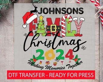 May include: A Christmas-themed design featuring the text "Johnsons Family Christmas 2024 Making Memories Together" with festive illustrations of a Christmas tree, candy canes, and a Santa hat. The design is ready for heat transfer to a t-shirt or other fabric.
