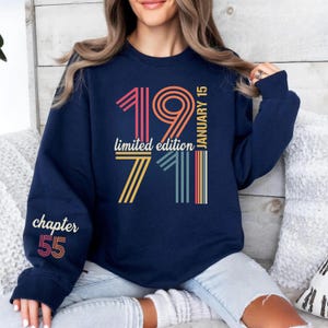 May include: Navy blue sweatshirt with retro-style text and graphics. The design includes the numbers "1971" and "55" with the words "limited edition" and "chapter". The text "January 15" is also present.