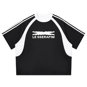 以下が含まれることがあります： 「LE SSERAFIM」の文字が入った、黒と白の半袖Tシャツ。 白いメッシュパネルと袖に白いストライプが入っています。 丸いネックラインです。