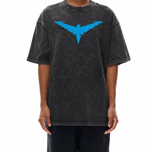May include: Dark gray t-shirt featuring a blue stylized bird emblem. The shirt has a vintage, washed appearance and a crew neck. The short-sleeved top is paired with black pants. The graphic is centered on the chest.
